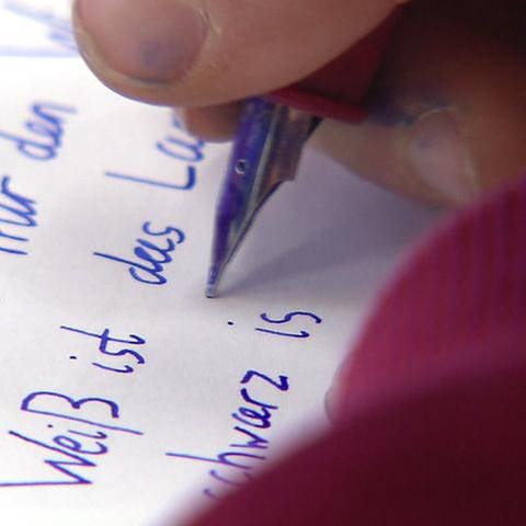 Ein Kind schreibt mit einem Füller auf ein Stück Papier