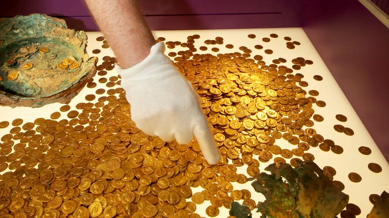 Der Trierer Numismatiker Karl-Josef Gilles platziert am 23.08.2013 im Landesmuseum in Trier (Rheinland-Pfalz) römische Goldmünzen in einer Vitrine.