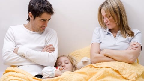 Tochter schläft zwischen den Eltern im Ehebett, Eltern sind genervt