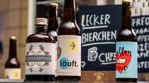 "Lecker Bierchen" steht auf der Tafel hinter verschiedenen Craft-Beer-Flaschen: Handwerklich gebrautes Bier sorgte für eine Wiederentdeckung und Wiederbelebung alter, regionaler Bierstile