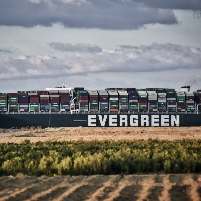 Das Containerschiff "Ever Given" fährt über den Suezkanal. Die durch die Corona-Krise ausgelösten weltweiten Logistik-Probleme und die Folgen des Suezkanal-Staus machen großen deutschen Handelsketten zu schaffen