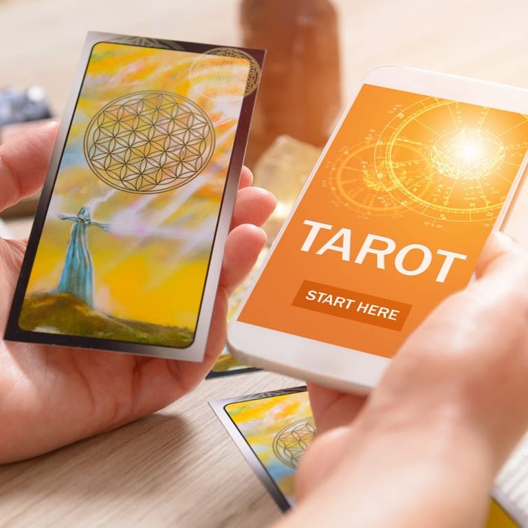 Tarotkarten und Smartphone mit Wahrsage-App: Auf Social Media bieten spirituelle Coaches Instagram-Lives zu Yoga und Meditation an, posten Kacheln zu Selbstliebe und positivem Denken oder legen Tarot-Karten. 