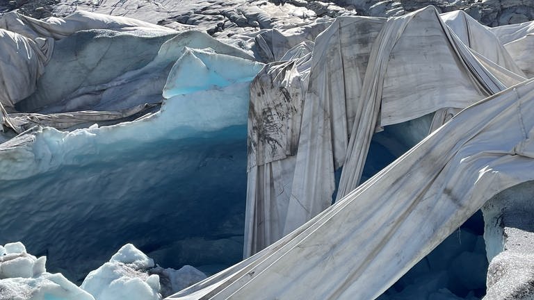 Eine Nahaufnahme vom Rand der Grotte. Es wäre schlicht unmöglich, den gesamten Gletscher mit Textilplanen abzudecken, um die Schmelze zu bremsen. Der Rettungsversuch gilt allein dem Tourismus-Unternehmen Eisgrotte. (August 2022)