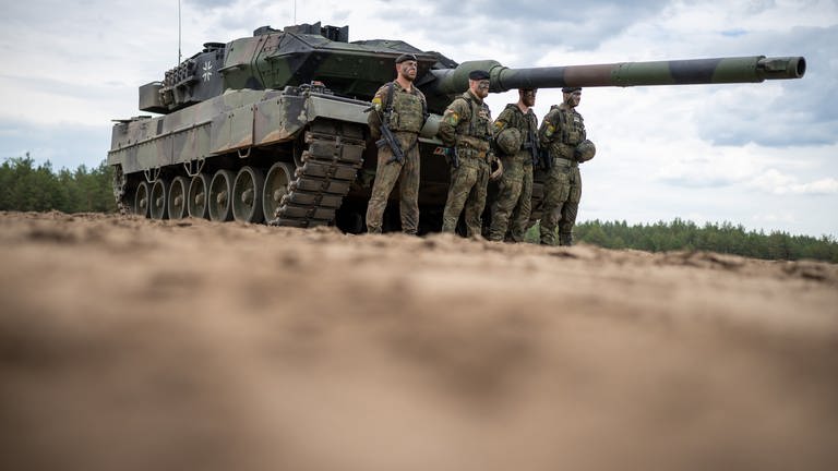 Ein Leopard 2 Panzer der Bundeswehr der NATO Enhanced Forward Presence Battle Group (eFP-Bataillon) steht beim Besuch von Kanzler Scholz im Camp Adrian Rohn. Kaum ein Waffensystem hat eine derartige Revolution ausgelöst wie der Panzer. Heute sind es Hochleistungsmaschinen, wesentlich schneller als ihre Vorgänger vor 100 Jahren – und durch den Angriffskrieg Russlands auf die Ukraine im Fokus der aktuellen Diskussion.