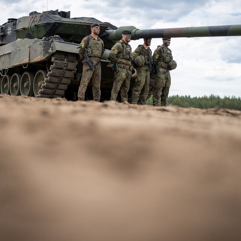 Ein Leopard 2 Panzer der Bundeswehr der NATO Enhanced Forward Presence Battle Group (eFP-Bataillon) steht beim Besuch von Kanzler Scholz im Camp Adrian Rohn. Kaum ein Waffensystem hat eine derartige Revolution ausgelöst wie der Panzer. Heute sind es Hochleistungsmaschinen, wesentlich schneller als ihre Vorgänger vor 100 Jahren – und durch den Angriffskrieg Russlands auf die Ukraine im Fokus der aktuellen Diskussion. (Foto: picture-alliance / Reportdienste, picture alliance/dpa | Michael Kappeler)