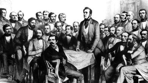 Die zeitgenössische Darstellung zeigt den liberalen Politiker Heinrich Freiherr von Gagern (Mitte), den Präsidenten der Frankfurter Nationalversammlung 184849, stehend inmitten von Abgeordneten des Parlaments