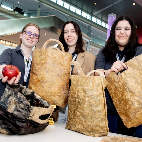 Die Teilnehmerinnen Anja Armstrong (l-r), Jennifer Boronowska und Seyma Celik aus Rüsselsheim am Main stellen beim Wettbewerb „Jugend forscht“ ihre kompostierbaren Einwegtüten aus Biokunststoff vor.