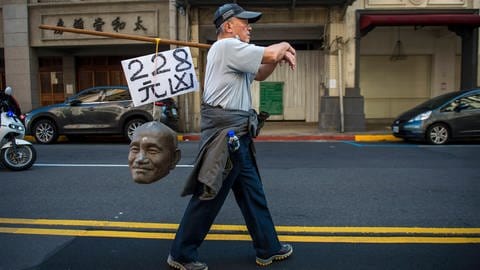 Ein Mann trägt am 28. Februar 2023 den von einer Statue Chiang Kai-sheks abgetrennten Kopf durch die Straßen Taipehs, um an das 228-Massaker von 1947 zu erinnern. Die Protestierenden fordern die Entfernung der Statuen und anderer Monumente des ehemaligen Diktators.  (Foto: IMAGO, IMAGO / ZUMA Wire)