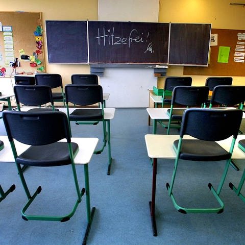 Ein leeres Klassenzimmer und an der Tafel steht Hitzefrei (Foto: IMAGO, IMAGO / Horst Rudel)