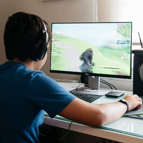 Ein Jugendlicher am Schreibtisch sitzend und spielt ein Computerspiel