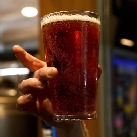 Ein Bierglas wird mit spitzen Fingern angefasst.