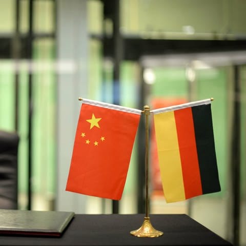 Fähnchen von China (l) und Deutschland stehen auf einem Tisch
