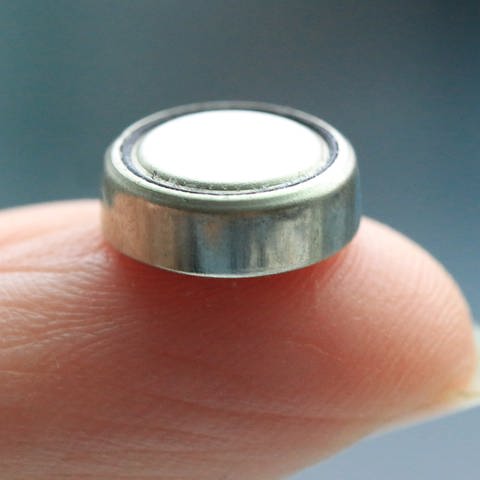 Eine sogenannte «Knopfzellen» wird auf einem Finger gehalten.