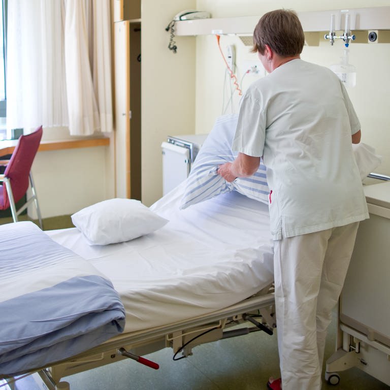 Eine Krankenpflegerin bereitet in einem Krankenzimmer ein Patientenbett vor. (Foto: picture-alliance / Reportdienste, picture alliance / dpa | Daniel Karmann)