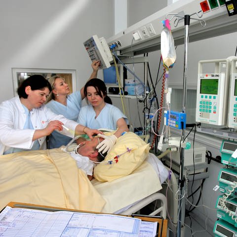 Im Intensivbereich für Neurologie wird ein Schlaganfall-Patient von einer Oberärztin untersucht und die umfassende Medizintechnik von den Schwestern überwacht.