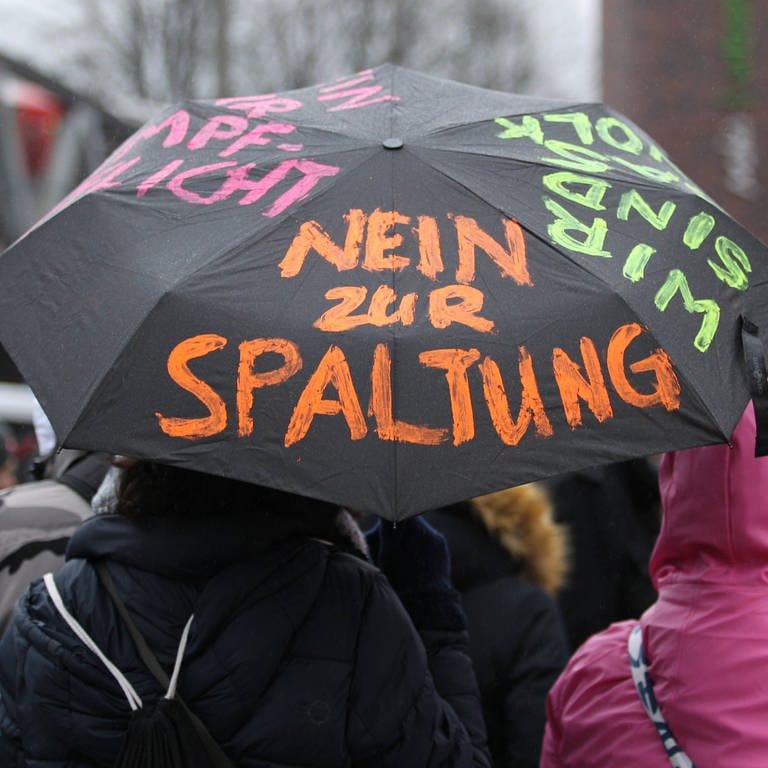 Ein Regenschirm mit der Aufschrift "Nein zur Spaltung" bei einer Demonstration von Kritikern der Corona-Maßnahmen. (Foto: IMAGO, IMAGO / Hanno Bode)
