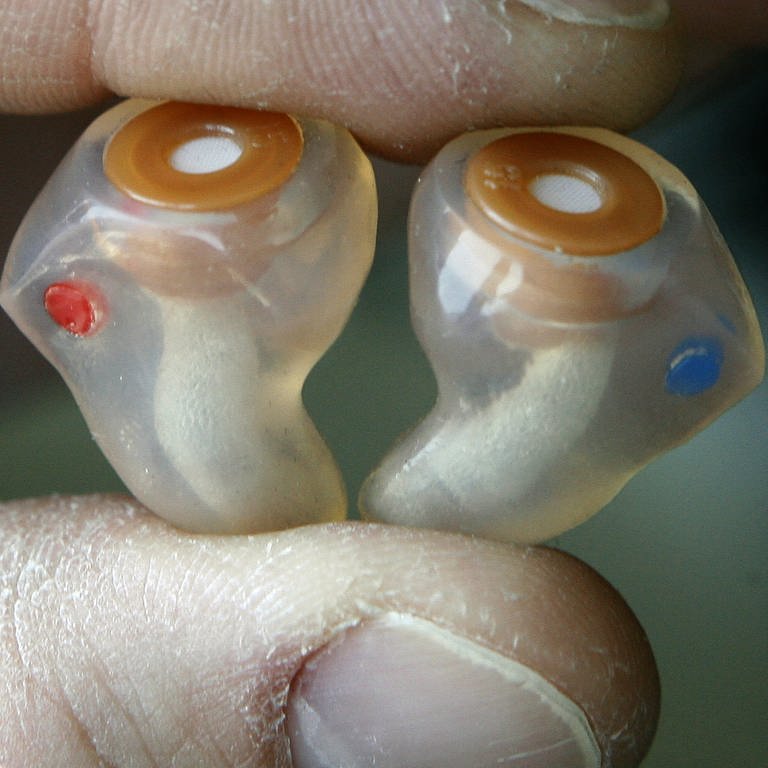 Ein Mann hält einen Gehörschutz in seinen Händen, der individuell für das Ohr des Benutzers geformt wird. 