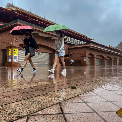 Taiwan: Zwei Frauen mit Regenschirmen laufen bei starkem Regen und Wind.