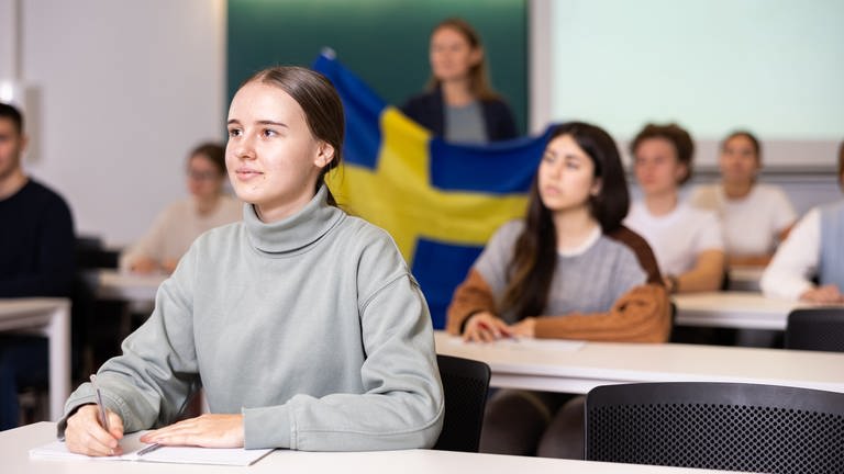 Junge Studentin hört sich aufmerksam eine Vorlesung in einem Klassenzimmer an (Foto: IMAGO, IMAGO / Pond5 Images)