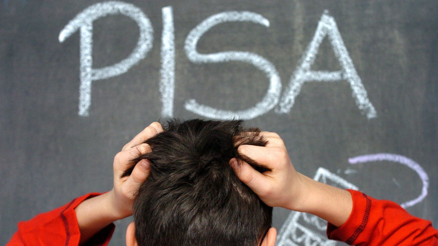 Ein von hinten stehender Schüler rauft sich die Haare, vor ihm das an die Tafel geschriebene Wort PISA. (Foto: picture-alliance / Reportdienste, picture-alliance / DPA / APA / picturedesk.com | DPA)