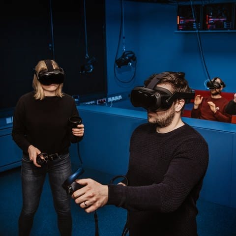 Menschen stehen mit VR-Brillen im Tatort-Virtual-Reality-Raum (Holodeck), so können Tatorte dreidimensional exakt nachgebildet und begangen werden. (Foto: Bayerisches Landeskriminalamt (LKA))