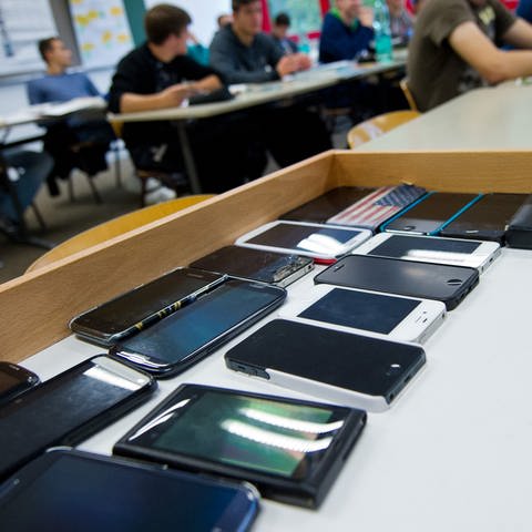 Symbolbild: Handys liegen im Unterricht in einer Kiste