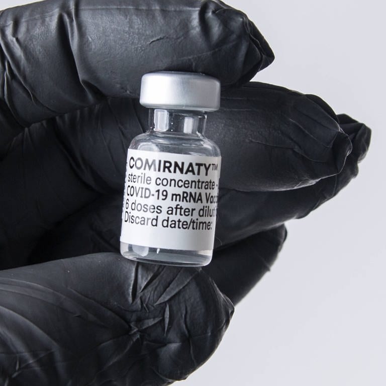 Eine Person mit Schutzhandschuh hat eine Ampulle mit dem mRNA-Impfstoff Comirnaty. (Foto: IMAGO, IMAGO / Fotostand)