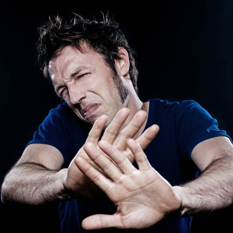 Mann hält mit angeekeltem Gesicht abwehrend die Hände vor sich: Ekel ist ein uralter Schutzmechanismus. Die körperlichen Reaktionen sind überall gleich – und doch ist vieles, was uns ekelt, kulturell erlernt.  (Foto: IMAGO, IMAGO / Panthermedia)