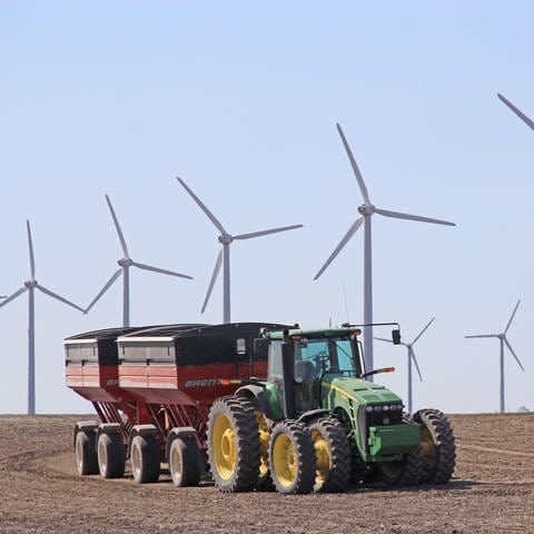 Traktor im Feld mit Windrädern (Foto: IMAGO, IMAGO / Pond5 Images)