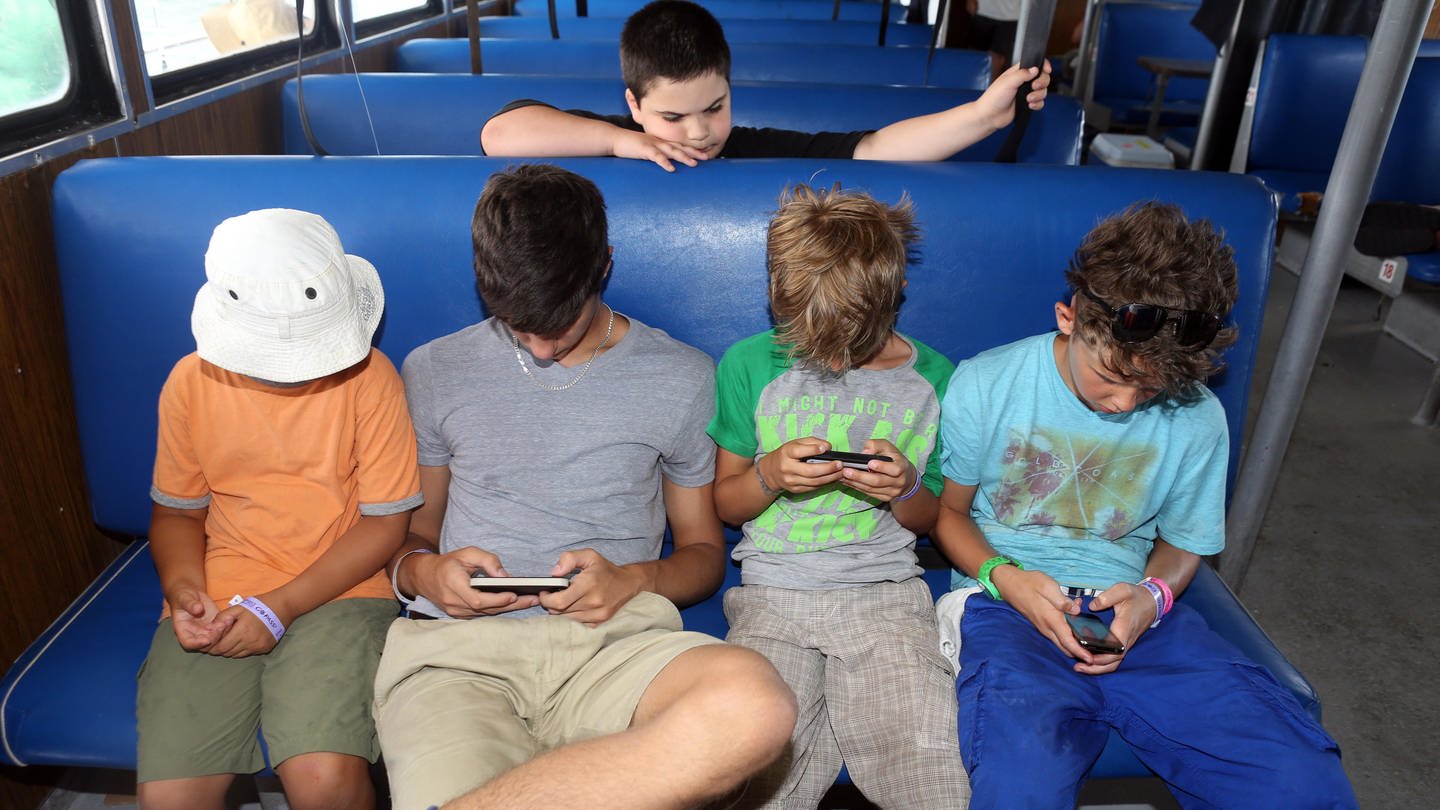 St. Pete Beach, Florida - Jungen schauen in einem Bus sitzend auf ihre Smartphones. (Foto: picture-alliance / Reportdienste, picture alliance / Caro | Sorge)