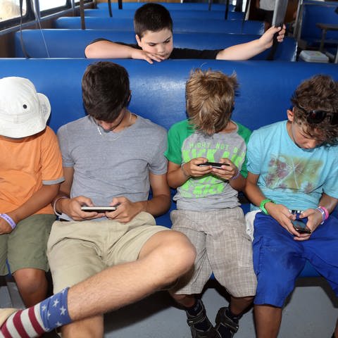 St. Pete Beach, Florida - Jungen schauen in einem Bus sitzend auf ihre Smartphones. (Foto: picture-alliance / Reportdienste, picture alliance / Caro | Sorge)