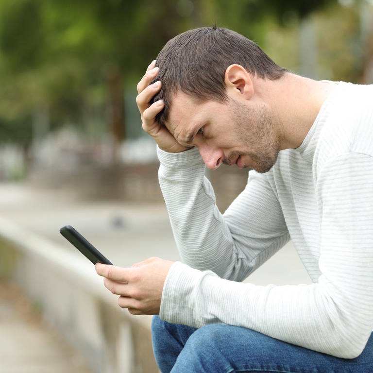 Ein trauriger erwachsener Mann liest schlechte Nachrichten auf dem Smartphone.  (Foto: IMAGO, IMAGO / Panthermedia)