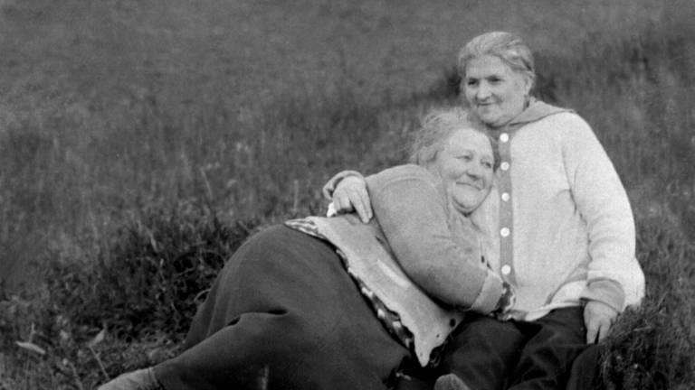 Zwei Frauen kuscheln um 1940 auf einer Wiese: Frauenliebende Frauen waren in Deutschland lange Zeit in der Öffentlichkeit nicht präsent, waren quasi unsichtbar. Sie wurden entweder gesellschaftlich ignoriert, angefeindet oder gar verfolgt.