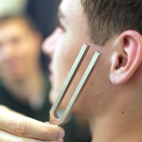 Symbolbild: Ein Jugendlicher wird beim Hals-Nasen-Ohrenarzt mit einer Stimmgabel untersucht.