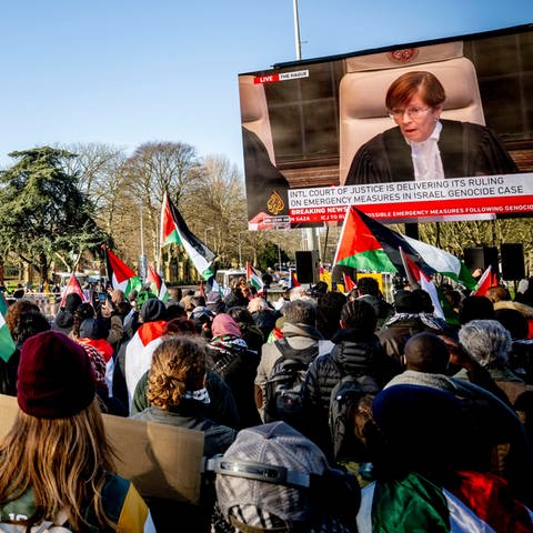 Demonstranten mit Flaggen Palästinas verfolgen auf einem Großbildschirm eine Übertragung aus dem Gericht: Demonstration in Den Haag vor dem Friedenspalast. Der Internationale Gerichtshof (IGH) prüft Südafrikas Vorwurf des Völkemords gegenüber Israel. Eine endgültige Entscheidung kann Jahre dauern, aber einstweilige Maßnahmen können bereits verhängt werden.