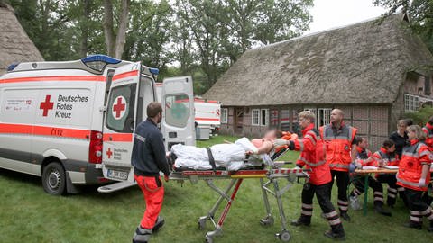 Eine verletzte Person wird am 4.9.2015 in Handeloh  Niedersachsen von Sanitätern zu einem Rettungsfahrzeug gebracht. In dem Tagungszentrum war es zu einer Massenvergiftung gekommen. (Foto: dpa Bildfunk, (c) dpa / picture alliance / Christian Butt/dpa)