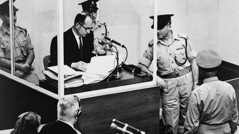 Adolf Eichmann sagt bei seinem Kriegsverbrecherprozess 1961 in Jerusalem aus. Eichmann wird von seinem Anwalt Robert Servatius (unten links) befragt. Eichmann wurde für schuldig befunden, die Massendeportation von Juden in Vernichtungslager in den von Deutschland besetzten Gebieten organisiert zu haben.