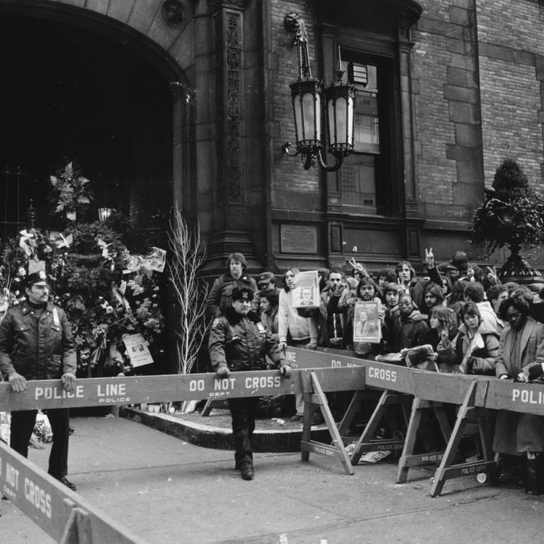 Die Polizei hält Fans am 9. Dezember 1980 vom Dakota-Gebäude in New York City zurück. Hier lebte John Lennon und am Eingang des Hauses wurde der Musiker am Tag zuvor ermordet. (Foto: picture-alliance / Reportdienste, picture alliance / AP | MARIO CABRERA)