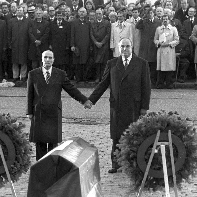 Der französische Staatspräsident Francois Mitterrand (links) und Bundeskanzler Helmut Kohl reichen sich am 22.9.1984 über den Gräbern von Verdun die Hand (Foto: picture-alliance / Reportdienste, (c) dpa - Fotoreport)