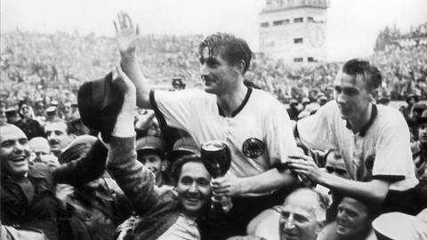 Die deutschen Fußballspieler Fritz Walter (mit dem Pokal in den Händen) und Horst Eckel werden am 4. Juli 1954 von Fans frenetisch gefeiert und auf den Schultern durch das Stadion getragen. Mit einem 3:2--Sieg über Ungarn im Endspiel der Fußball-Weltmeisterschaft 1954 in BernSchweiz gewann Deutschland den Titel. (Foto: picture-alliance / Reportdienste, Picture Alliance)