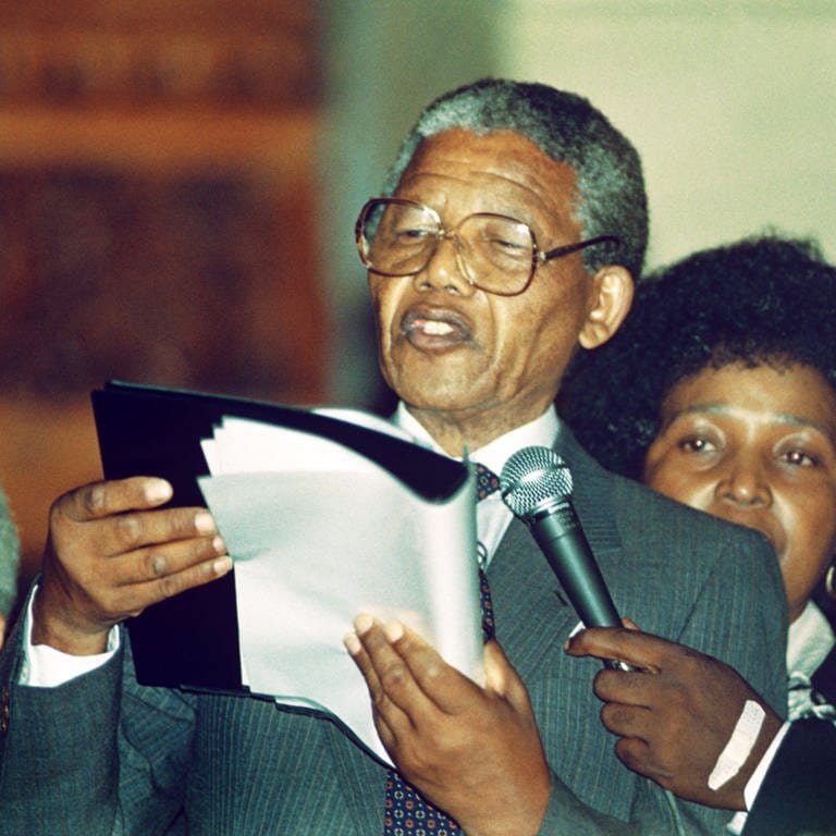 Der Führer der südafrikanischen Befreiungsbewegung ANC, Nelson Mandela (Mitte), hält nach seiner Freilassung aus dem Gefängnis am 11.2.1990 eine Rede in Kapstadt. Hinter ihm seine Frau Winnie Mandela. Der spätere Nobelpreisträger und Politiker wurde der erste schwarze Staatspräsident des Landes (1994-1999). Er wurde 1964 wegen seines Kampfes gegen das Apartheidregime zu lebenslanger Haft verurteilt und 1990 freigelassen. 1993 bekam er gemeinsam mit Präsident Frederik de Klerk den Friedensnobelpreis.