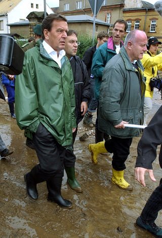 Bundeskanzler Gerhard Schröder (SPD, links) und der sächsische Ministerpräsident Georg Milbradt (CDU) gehen am 14. August 2002 durch die nach dem Hochwasser verwüstete sächsische Kreisstadt Grimma (Foto: dpa Bildfunk, picture alliance / dpa | Waltraud Grubitzsch)