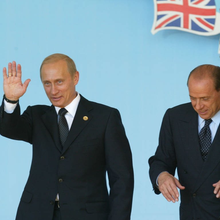NATO-Russland-Rat: Russlands Präsident Wladimir Putin winkt im Beisein von US-Präsident George W. Bush (rechts) und Italiens Ministerpräsident Silvio Berlusconi nach Unterzeichnung eines Vertrages über eine neue Zusammenarbeit beim Russland-NATO-Gipfel am 28. Mai 2002 in Pratica di Mare bei Rom