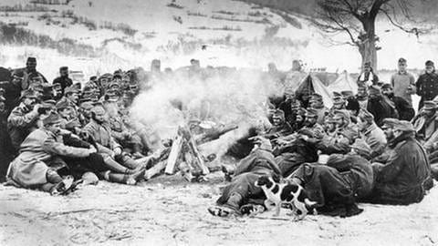 Soldaten sitzen um ein Lagerfeuer herum und wärmen sich auf, Schneelandschaft im Hintergrund. (Foto: SZ Photo - Scherl)