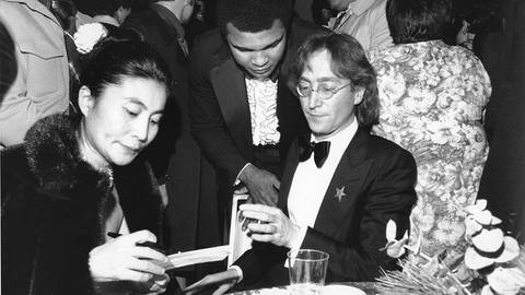 John Lennon, seine Frau Yoko Ono und Muhammad Ali am 20. Januar 1977 im Kennedy Center in Washington, DC. Sie nehmen an der Gala zu Ehren des gewählten Präsidenten Jimmy Carter teil am Vorabend seiner Amtseinführung. (Foto: picture-alliance / Reportdienste, picture alliance / ASSOCIATED PRESS)