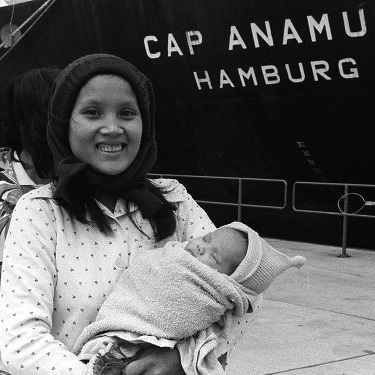Eine junge Frau mit Kind steht vor demm Rettungsschiff "Cap Anamur" (Foto: picture-alliance / dpa, picture-alliance / dpa -)