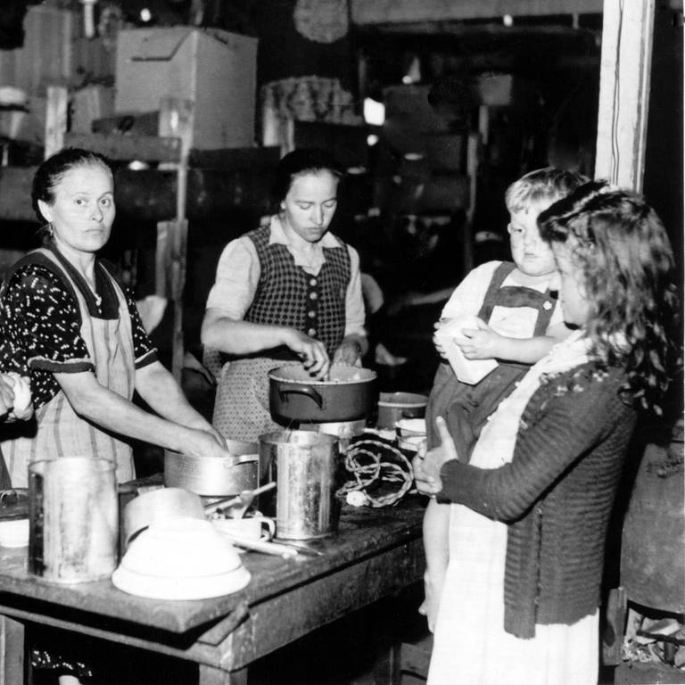 Frauen bereiten 1948 an einem Tisch im bayerischen Flüchtlingslager Allach Mahlzeiten zu (undatierte Aufnahme von 1948) (Foto: dpa Bildfunk, picture alliance/dpa | Georg Göbel)