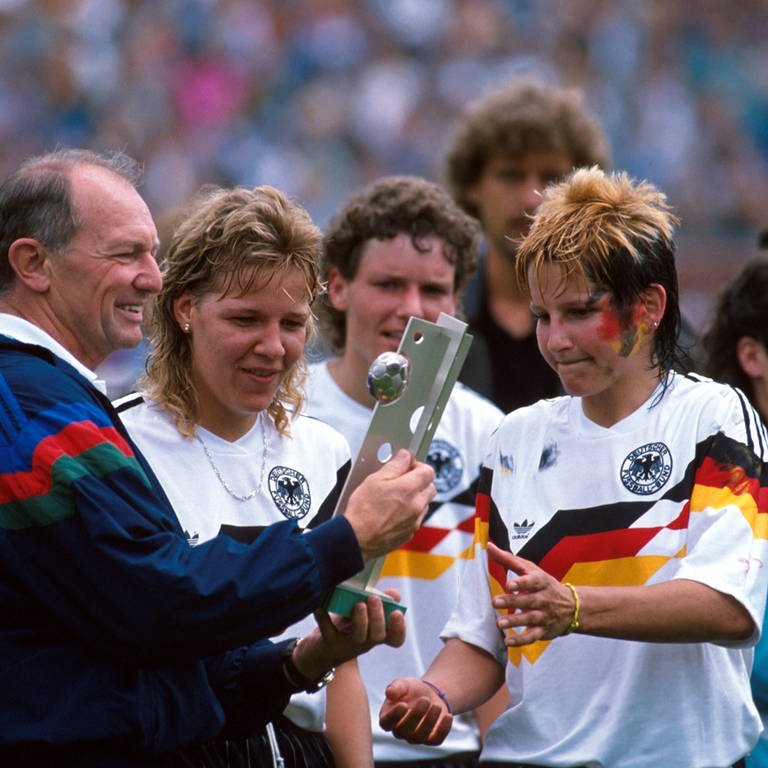 Fußball-Bundestrainer Gero Bisanz übergibt den EM-Pokal an Spielerin Ursula Lohn (2.v.r.)