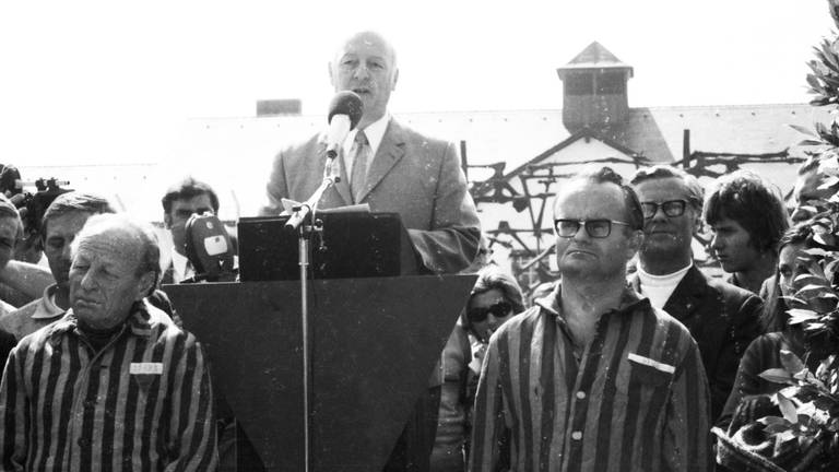 Die israelische Olympiamannschaft gedenkt am 1.9.1972 beim Besuch des ehemaligen Konzentrationslagers Dachau der Opfer des nationalsozialistischen Terrors und legt einen Kranz nieder. Vier Tage später sind die israelischen Sportler selber Opfer eines Terroranschlags.