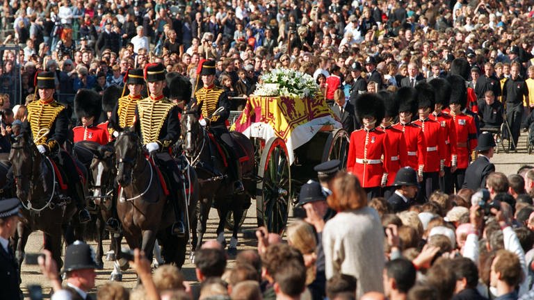 Begleitet von der Königlichen Garde wird die Geschützlafette mit Prinzessin Dianas Sarg am 6. September 1997 durch die Londoner Innenstadt zur Westminster Abbey gezogen. Etwa zwei Millionen säumen den Trauerzug der verunglückten Prinzessin von Wales.